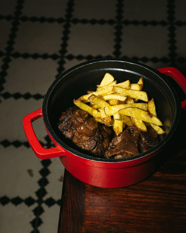 Cua de bou guisada a foc lent amb patates fregides.
 Per sucar-hi pa. I brindar amb una copa de vii negre.

 Rabo de buey guisado a fuego lento con patatas fritas.
 De los de mojar pan. Y acompañar con una copa de viino tinto.

 Slow-cooked oxtail stew with crispy fries.
 Bread-dipping good. Best with a glass of red wine.